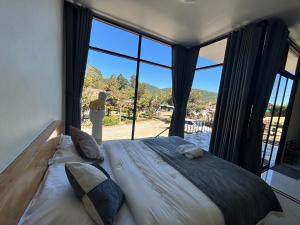 a bedroom with a large bed with a large window at อินทนนท์ บ้านพักเล่าจู Inthanon Laoju House in Ban Na Yang
