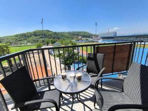 a table and chairs on a balcony with a view of a stadium at Lux Apartman Crnjanski IV, Jagodina in Jagodina