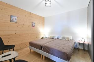 大博尔南Appartement Le Barat'ski的带床和木墙的卧室