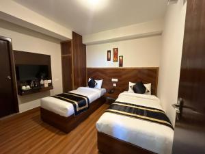 ガントクにあるHotel Freesia Staysのベッド2台とテレビがあるホテルの部屋