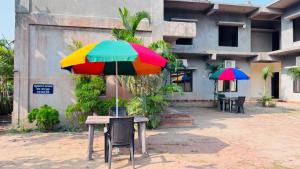 un tavolo con un ombrello colorato sopra di esso di Samarth Beach Resort a Malwan