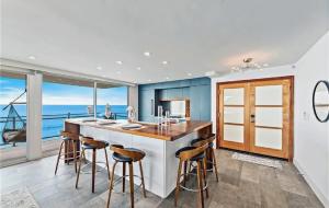Una cocina con una gran isla con taburetes de bar. en Luxury Three-Bedroom Oceanfront Residence With Panoramic Coastal Views, en Laguna Beach