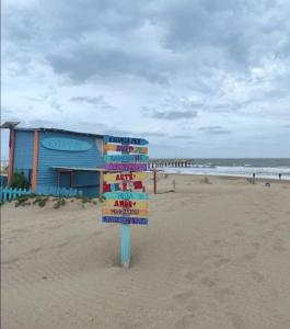 ein Schild am Strand mit einem Gebäude im Hintergrund in der Unterkunft Gesell130 in Villa Gesell