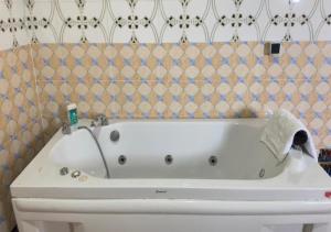 アシニにあるAKl RESIDENCEのタイル張りの浴室にある白い浴槽 +4枚の写真