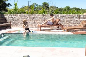 a man and a woman sitting in a swimming pool at Pousada SáGuest in Praia do Rosa