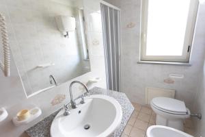 Un baño con lavabo, inodoro y espejo. en San Domenico Village, en Fitili
