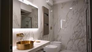 a bathroom with a gold sink and a toilet at Hotel Wellness Magione Papale in LʼAquila