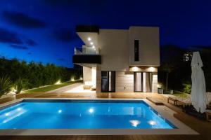 a swimming pool in front of a house at night at Luxury Villa Positiva in Vir