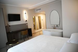 a white bedroom with a bed and a tub and a sink at Hotel Wellness Magione Papale in LʼAquila