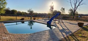 a swimming pool with a blue slide in a park at Loubad Guest Farm in Modimolle