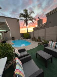 a backyard with a pool and a palm tree at AquaPalms Hideaway - Family Friendly Pool - Hot Tub - Indoor Braai in Cape Town