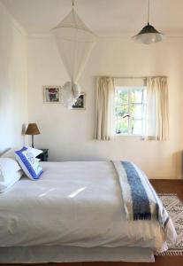 a large white bed in a bedroom with a window at Eensgevonden Vineyard Cottages in Rawsonville
