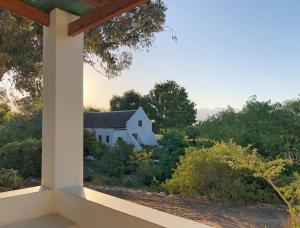 a view of a white house from a porch at Eensgevonden Vineyard Cottages in Rawsonville