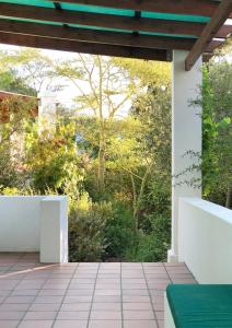 an outdoor patio with white walls and trees at Eensgevonden Vineyard Cottages in Rawsonville