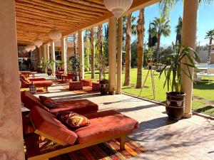 eine Terrasse mit Sofas, Tischen und Palmen in der Unterkunft Palais Bohemia in El Rhechat