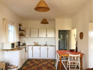 a kitchen with white cabinets and a table at Eensgevonden Vineyard Cottages in Rawsonville