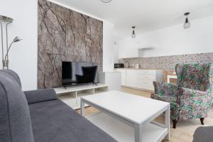 a living room with a couch and a tv at Charming Little Laguna Apartment with SPA & Fitness by Noclegi Renters in Międzywodzie +12 photos