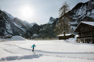 LaVida Peak Mountain Retreat in Frutigen في Wengi bei Frutigen: شخص على الزحافات في الثلج بالقرب من النزل