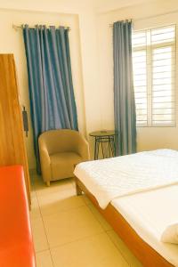 a bedroom with a bed and a chair and a window at Bảo Anh Motel in Hải Dương