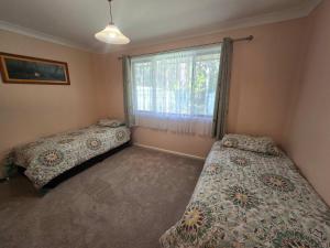 Un dormitorio con dos camas y una ventana. en Seascape Macleay Street - walk to beach, en Narrawallee 17 fotos más