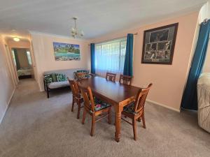 Un comedor con una mesa y sillas y un sofá. en Seascape Macleay Street - walk to beach, en Narrawallee