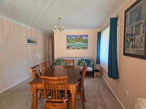 Un comedor con mesa y sillas de madera. en Seascape Macleay Street - walk to beach, en Narrawallee