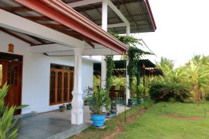 un portico anteriore di una casa bianca con un tetto rosso di Wadula Resort a Nochchiyagama