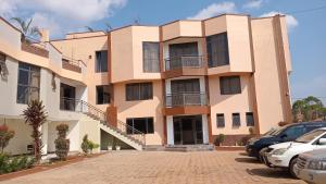 a building with cars parked in front of it at Opal Heights Hotel Nansana in Kyebando