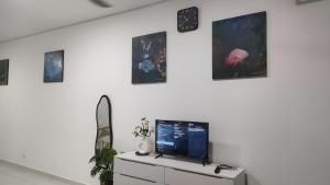 un soggiorno con TV su una parete bianca di The Duta Loft a Bandar Puncak Alam