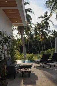 een patio met 2 ligstoelen en een zwembad bij Chic Koh Phangan Villa with Pool Bliss in Ko Phangan