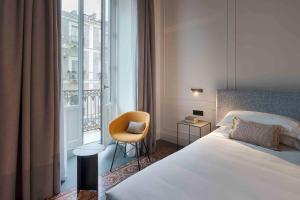 a hotel room with a bed and a chair and a window at Habitat Boutique Hotel in Catania