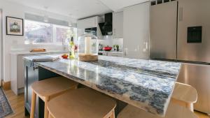 a kitchen with a marble counter top and chairs at Rutherglen in Beaumaris