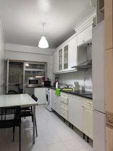 a kitchen with white cabinets and a table in it at Bliss in Lisbon Humberto Delgado Airport