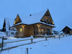 a log cabin in the snow with lights on at U Sabały in Chochołów