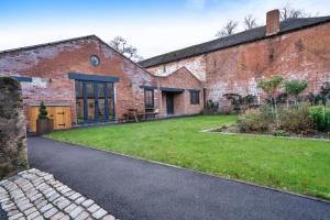 an external view of a brick building with a grass yard at Finest Retreats - Courtyard View at Longford in Hollington