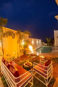 um pátio com duas cadeiras e uma piscina à noite em ELIVAAS Le Aravella 3 BHK Villa with Gazebo, Balcony & Private Pool em Lakāwās
