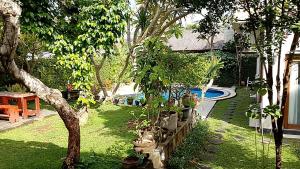 a garden with trees and potted plants and a pool at Casavina residen kubu manyar 202 in Dalung
