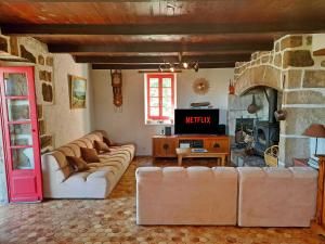 ein Wohnzimmer mit Sofas und einem TV. in der Unterkunft La calade de Joux in Chassiers