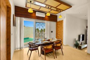 uma sala de jantar com mesa e cadeiras e uma janela em ELIVAAS Le Aravella 3 BHK Villa with Gazebo, Balcony & Private Pool em Lakāwās