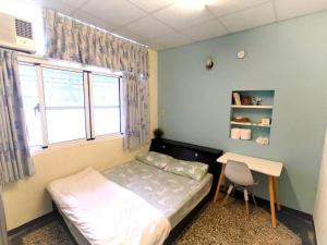 a bedroom with a bed and a desk and a window at 想來就來-台南包棟民宿-電動麻將ktv可寵物 in Tainan