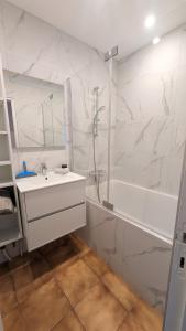 a white bathroom with a sink and a shower at L'Acacia, F2 terrasse et jardin,plage à 400mètres in Houlgate