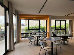 ein Restaurant mit Tischen und Stühlen und Fenstern in der Unterkunft Fantini Club Hotel in Cervia