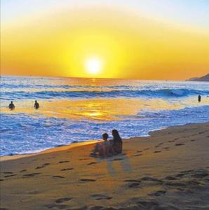 two people sitting on the beach watching the sunset at TOROS BULVAR Cozy fancy Sea view next to the Beach and the Mall, in the mid of Alanya Mahmutlar! in Mahmutlar
