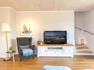 a living room with a tv and a chair at Sonnenbirke in Fuhlendorf