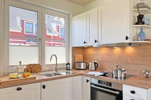 a kitchen with white cabinets and a sink and a window at Sonnenbirke in Fuhlendorf +29 photos