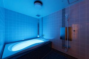 ein Badezimmer mit einer Badewanne und einer Dusche mit blauen Lichtern in der Unterkunft ホテル Ano in Kanuma