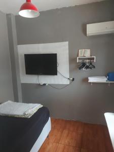 een slaapkamer met een flatscreen-tv aan de muur bij Kitinete final de rua centro in Itajaí