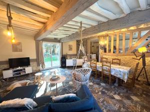 una sala de estar con un sofá y una mesa en La Maison Labonnechose - Piscine chauffée - Calme - Jeux, en Notre-Dame-de-Fresnay