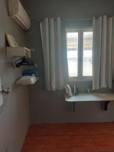 een kamer met een raam en een plank met een telefoon bij Kitinete final de rua centro in Itajaí