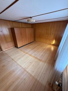 LaVida Wave Lakeside Haven am Thunersee & Alps في ليسيغن: غرفة فارغة مع أرضية خشبية وجدار +8 صور